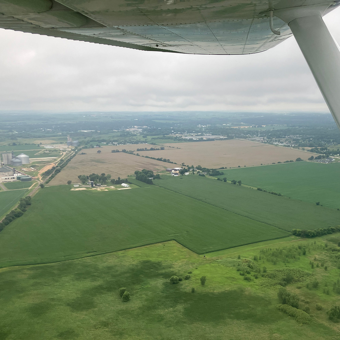 aerial view of farmland and underside of plane wing